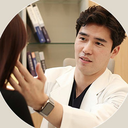Bác sĩ chuyên khoa phẫu thuật thẩm mỹ ngồi đối diện bệnh nhân trong phòng khám, vừa ra hiệu bằng tay vừa tư vấn