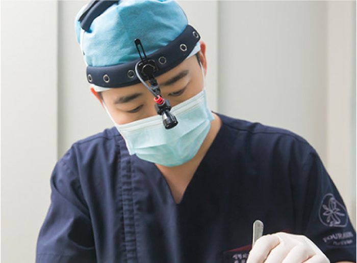 المدير الطبي د. Jegal Jeong-jae يستعد للجراحة وهو يمسك بالأدوات مرتديًا قبعة الجراحة والكمامة