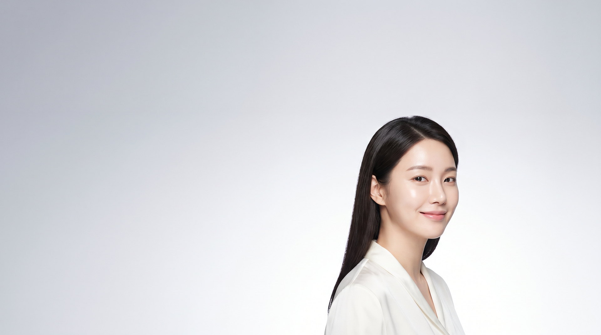 Female model with her head slightly turned, in front of a background that fades from cool gray to white