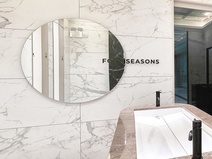 مرآة دائرية معلّقة على جدار رخامي مع حروف FOURSEASONS