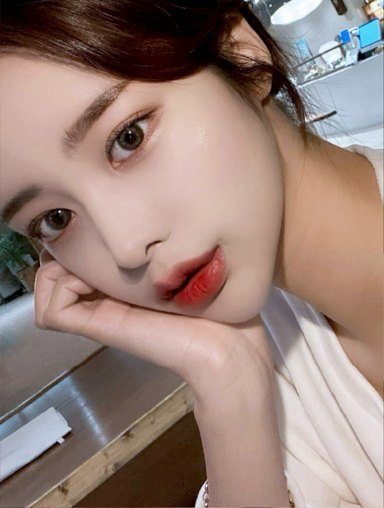Selfie of a woman by a window with her hand on her face, facing forward