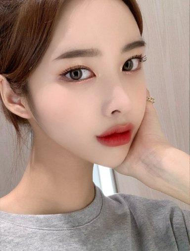 Selfie of a woman in a gray top with her head slightly raised