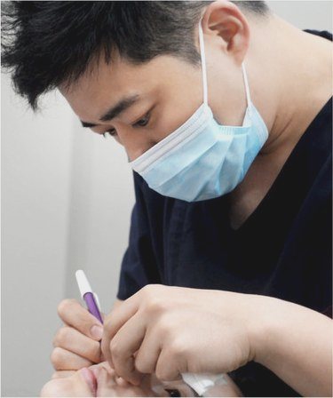 마스크를 쓰고 펜을 든 채 수술 계획을 살피는 제갈정재 대표원장