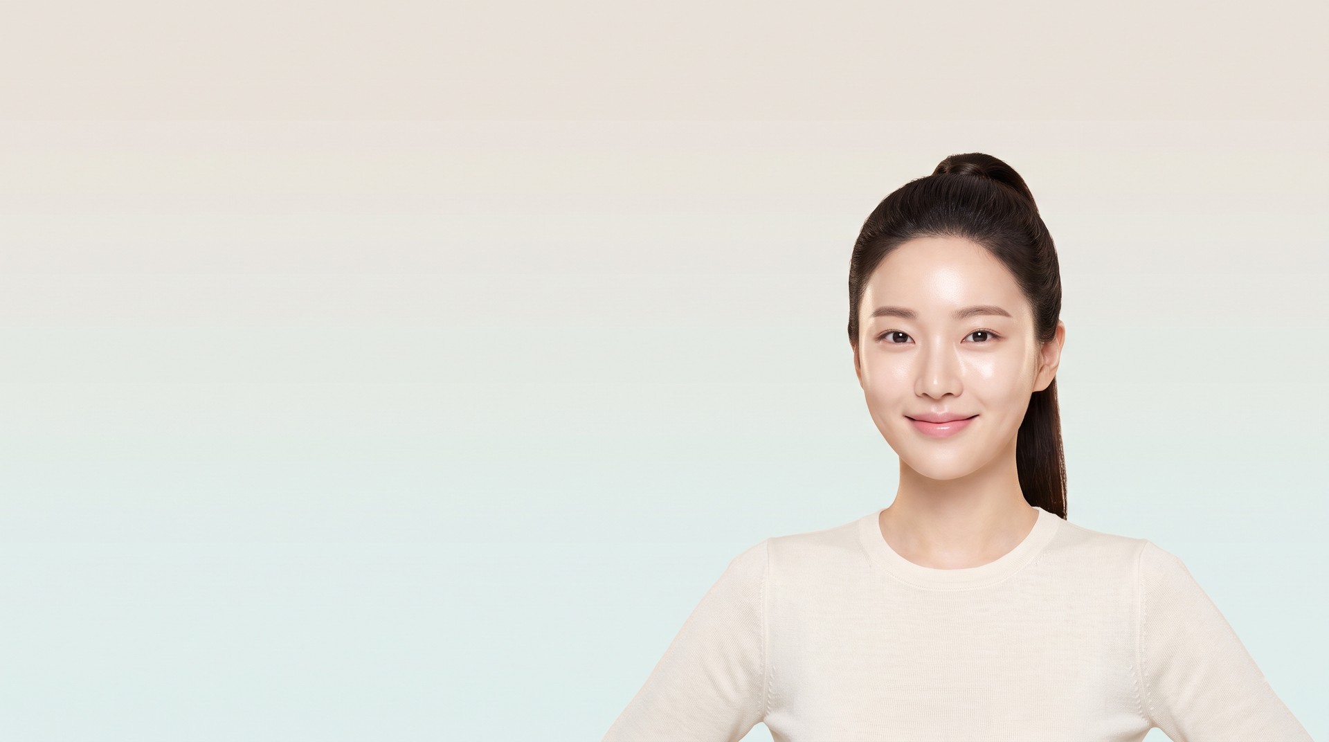 Female model facing forward against a background that blends from warm greige to pale aqua mint