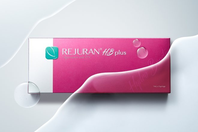 Kotak produk Rejuran HB Plus berwarna pink di atas latar gelombang putih